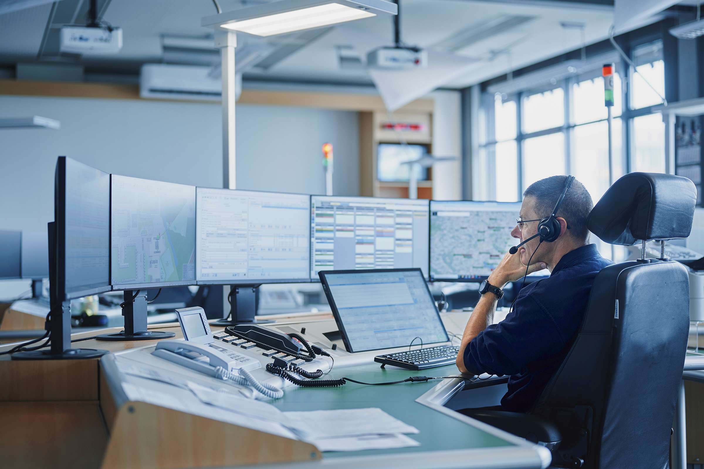 Mann sitzt in Leitstelle vor mehreren Monitoren.